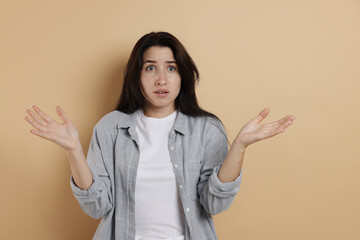 Worried woman suffering from panic attack on beige background