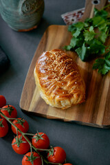 Delicious Savory Pastry with Sesame Seeds Served on a Wooden Cutting Board Alongside Fresh Tomatoes...