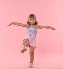 Cute little girl with wide open arms on pink background