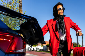Stylish latin man loading luggage into car trunk before road trip
