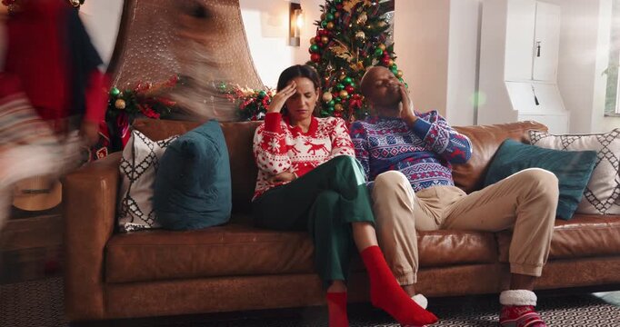 Frustrated parents, christmas or headache on sofa with chaos for burnout, ADHD kids or busy home. Tired, mom and dad with running children, anxiety or fatigue for stress in crazy living room or house