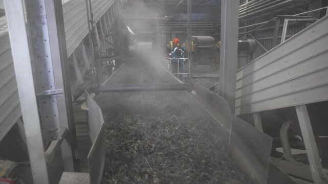 Powerful extrusion unit pushes thick rubber mass through metal chute. Highly mechanical scene in industrial surrounding of recycling plant