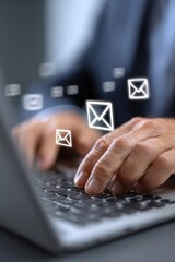 Closeup of hands typing on a laptop with email icons