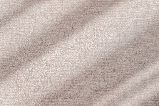 Abstract sunlight shadows on a neutral taupe beige velure cloth, aesthetic minimalist natural background with copy space