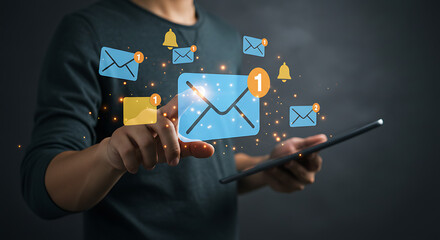 A person interacts with a futuristic interface, touching a digital email icon with a new message notification, surrounded by other floating alerts and holding a tablet.