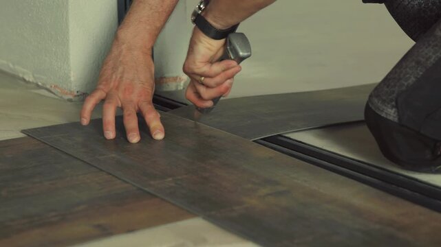 Construction worker installing vinyl laminate flooring