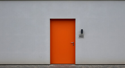 Striking visual of an orange door against a stark white building facade creating contrast and