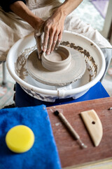 Close up of pottery artist's hands shaping a clay bowl on spinning throwing wheel in class or studio