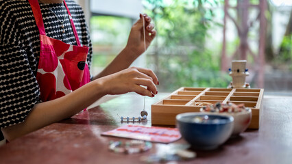 Painted nail woman pottery artist threading ceramic bead making colorful bracelet in class or studio
