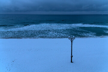 tranquil seascape with snow-covered beach and waves at dawn in winter
