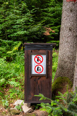Wooden garbage bin in the forest. Warning sign prohibiting littering in the forest