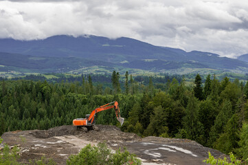 orange excavator works in the mountains