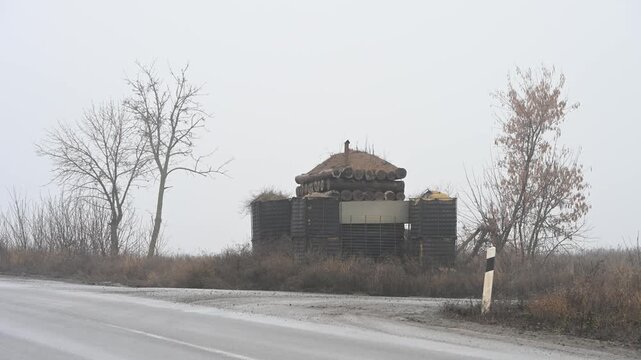 A makeshift military checkpoint made of tires and sandbags on the foggy outskirts of Kramatorsk, Ukraine. Fortifications like this are a common sight on roads near the Donbas frontline.
