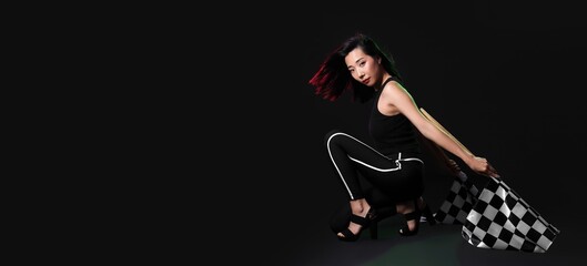 Beautiful Asian woman with racing flags on dark background with space for text