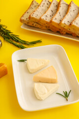 Plate with triangles of tasty processed cheese on yellow background