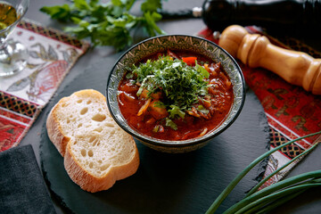 A Delicious Bowl of Hearty Soup Garnished with Fresh Herbs, Accompanied by a Slice of Bread, Set Against a Rustic Table Decorated with Greens and Spices
