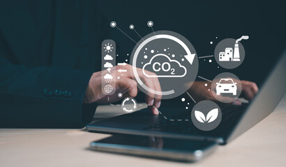 A person uses a laptop while interacting with digital icons related to CO2 emissions, sustainability, and environmental impact.