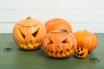 Carved Halloween pumpkins and spiders on color wooden table, closeup