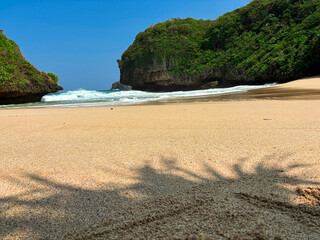 Obraz premium Paradise Found: A tranquil beach, adorned with soft, golden sand, invites you to immerse yourself in a haven of peace. With crystal-clear waters and lush, verdant hills.
