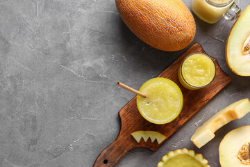 Wooden board with glasses of tasty melon smoothie on grey background