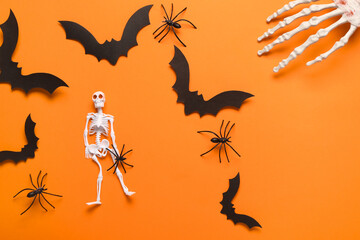 Composition with skeleton, hand, paper bats and spiders for Halloween celebration on orange...