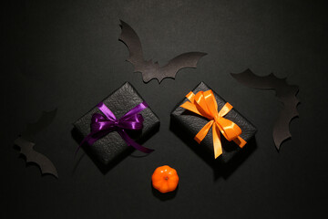 Paper bats with pumpkin for Halloween party and gift boxes on black background