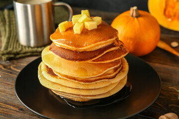 Plate of tasty pumpkin pancakes with honey on wooden table