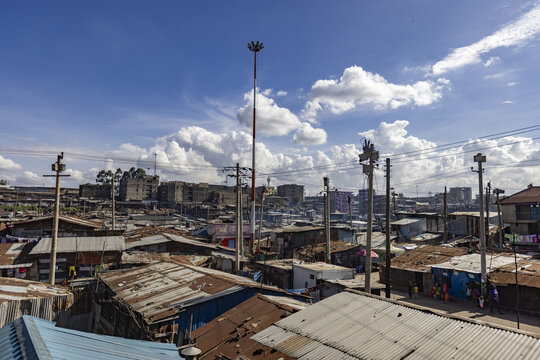 View of corrugated iron roofs contrasting with distant modern buildings under a bright sky with scattered clouds, Nairobi, Nairobi County, Kenya.