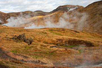 An awe-inspiring Icelandic landscape of a winding river flowing with hot water through grassy...