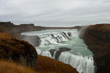 An icy winter waterfall plunges from a craggy mountain peak in Iceland, a natural beauty Gullfoss​ cascade, Iceland