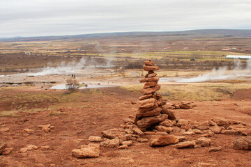 Geyser landscape with red rocks tower under a clear sky, in Golden Circle Iceland