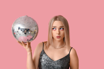 Beautiful thoughtful young woman with disco ball on pink background