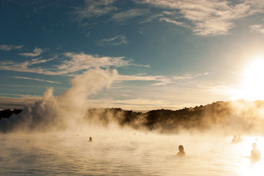 Awesome summer sunset over a tranquil lake, her silhouettes cast against the vibrant evening sky in Blue Lagoon, Iceland - Powered by Adobe