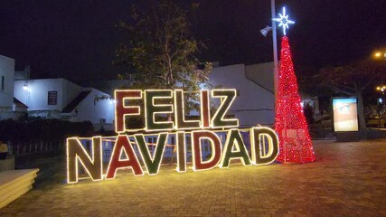 Merry Christmas in Spanish: Feliz Navidad sign with a christmas tree. Horizontal footage. - Powered by Adobe