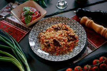 Delicious Platter of Savory Rice and Tender Meat Garnished with Fresh Vegetables and Accompanied by a Flavorful Salad and Herbs