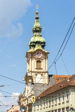 Close-up of the ornate clock tower with green dome from Stadtpfarrkirche zum Heiligen Blut in Graz, Austria.