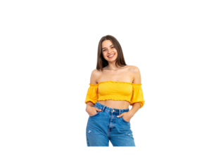 Cheerful brunette woman in a yellow offtheshoulder crop top and blue jeans smiling with hands in pockets.