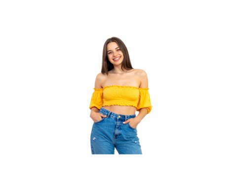 Cheerful brunette woman in a yellow offtheshoulder crop top and blue jeans smiling with hands in pockets.