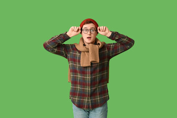 Emotional man in hat with eyeglasses and sweater on green background