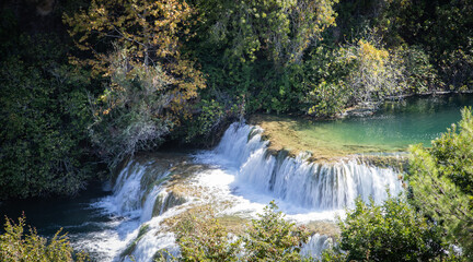  Peaceful waterfall in a Croatian national park surrounded by lush greenery and clear water. A...