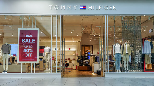 Tommy Hilfiger store front showcasing stylish clothing and promotional sale sign, inviting shoppers to explore trendy fashion options