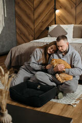 Fototapeta premium Young couple relaxing on bedroom floor with pet cat