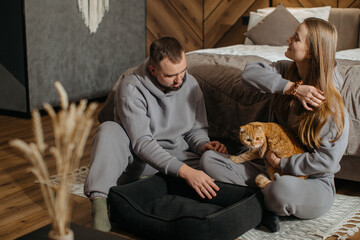 Fototapeta premium Couple relaxing at home with their scottish fold cat