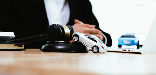 A lawyer in a suit uses a gavel near a toy car on a base, symbolizing legal judgment, car accident cases, and auto insurance law.