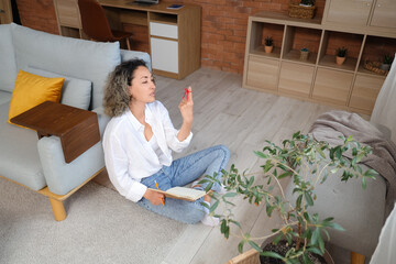 Beautiful middle-aged woman with red string on her finger trying to remember something at home....