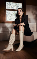 Elegant young woman in stylish clothing and knee-high boots.