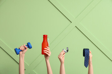 Female hands with dumbbell, water bottle, mouth piece and tie on green background. Prostate cancer...