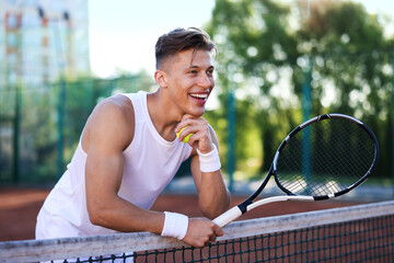 Young man with racket at tennis court
