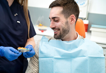 Smiling male patient during dental consultation with impression tray in a modern clinic