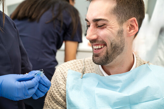Smiling man in his 30s at a dental checkup with orthodontic retainer in clinic